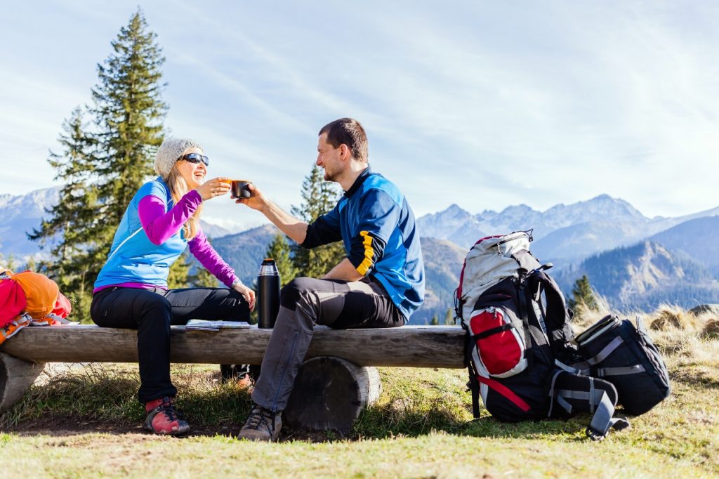 Couple hikers camping and drinking in mountains