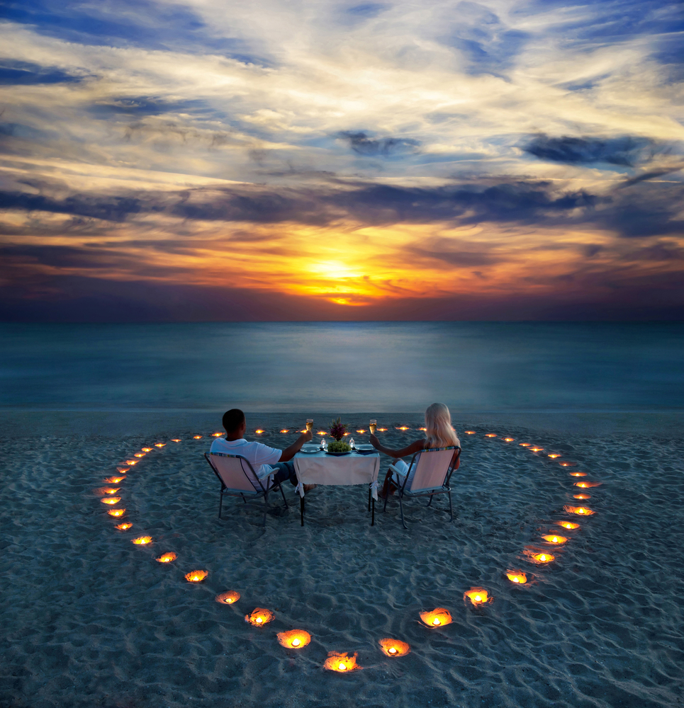 A young couple share a romantic dinner on the beach