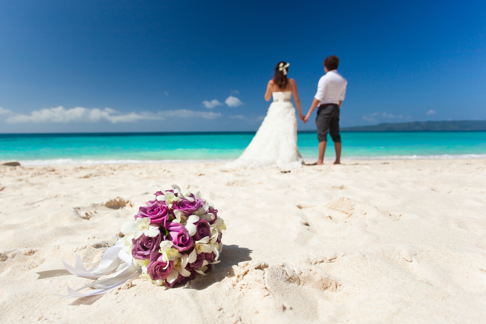 Wedding bouquet on wedding couple background, kissing at the beach