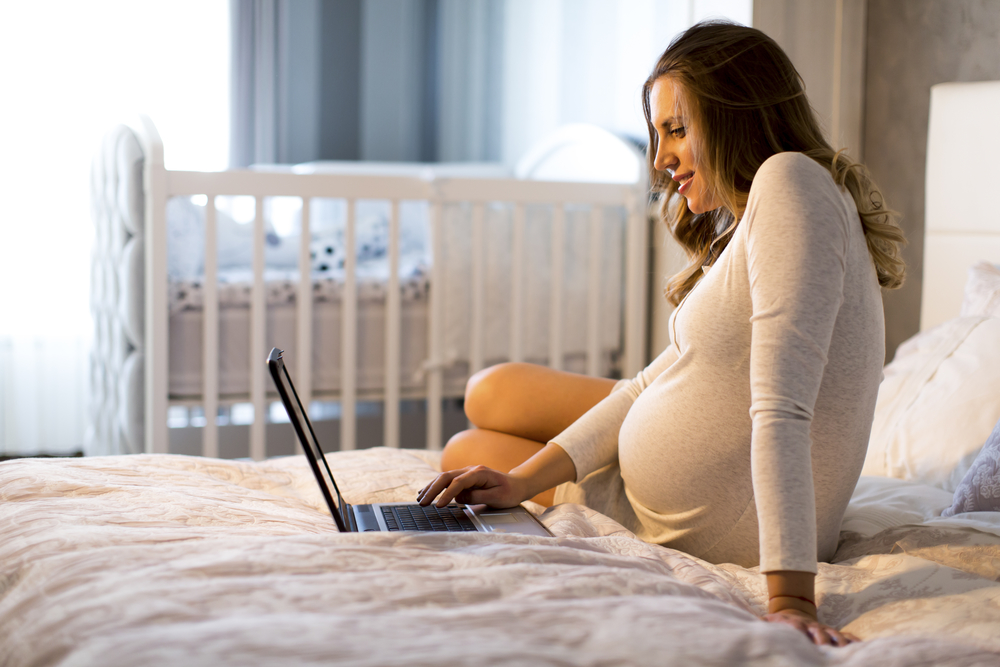 Pregnant Woman on computer adding to her Babylist baby registry