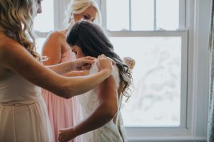 Bride and Bridesmaid Securing Wedding Dress